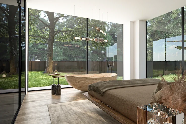 Glass walled bedroom with freestanding bathtub and garden view